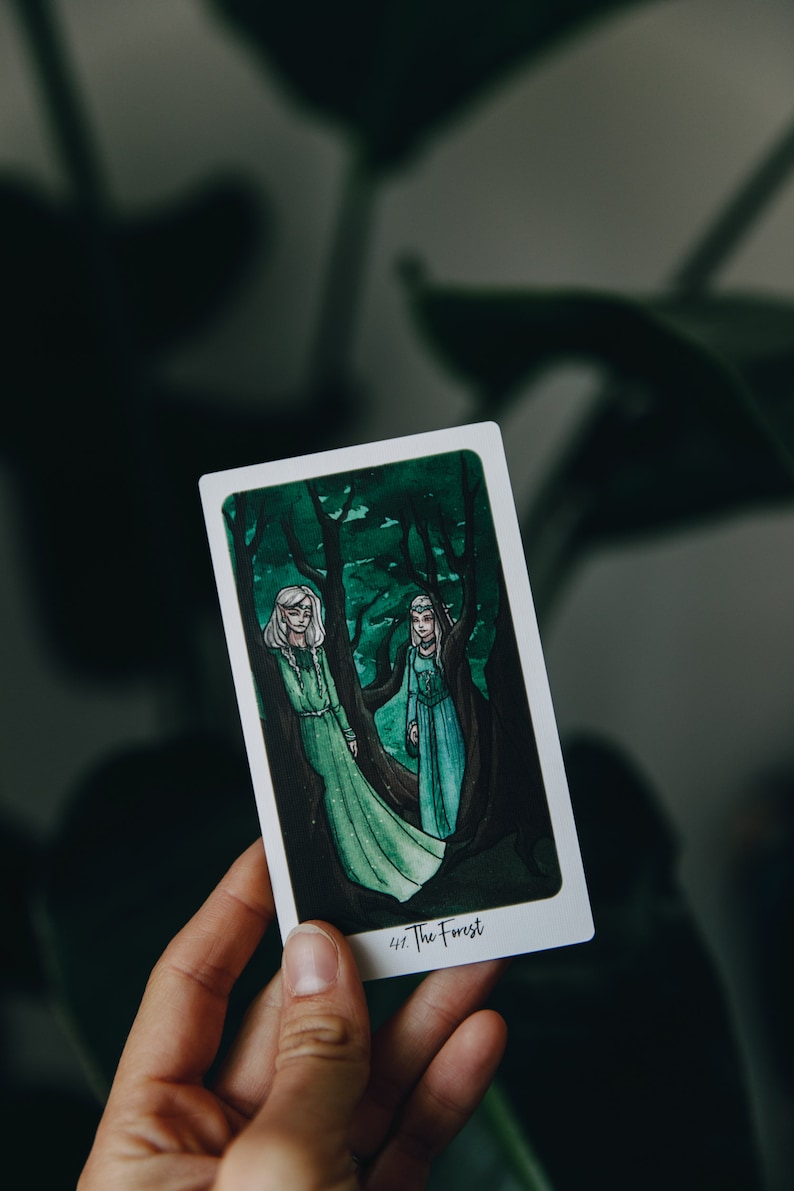 May include: A tarot card with a green and white illustration of two women standing in a forest. The card is titled "The Forest".