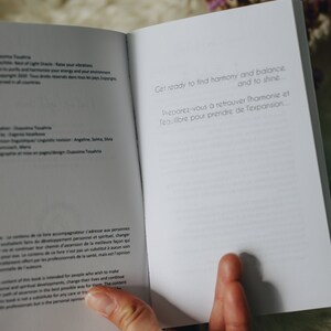 May include: Open book with white pages and text in French and English. The text reads "Get ready to find harmony and balance... and to shine... Preparez-vous &agrave; retrouver l'harmonie et l'&eacute;quilibre pour prendre de l'expansion..."