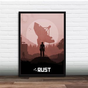 Op de afbeelding: Ingelijste poster met een silhouet van een rood en bruin landschap. Een grote schotelantenne domineert de achtergrond, met een figuur op de voorgrond. Het woord "RUST" staat in het wit onderaan de afbeelding.
