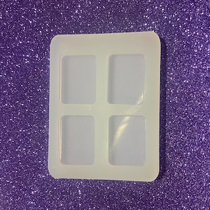 May include: A white silicone mold with four square cavities. The mold is designed for making resin crafts.