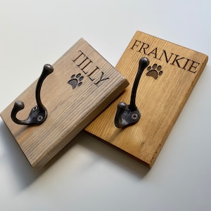 May include: Two wooden hooks with metal hooks and paw print designs. The hooks are labelled "Tilly" and "Frankie".