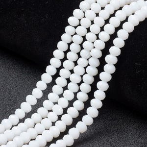 May include: Close-up of several strands of white, faceted beads. The beads are round and have multiple facets, giving them a sparkling appearance. The beads are strung together, perfect for crafting jewellery or other decorative items.