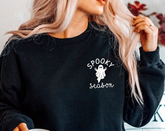 May include: Black sweatshirt with the text "Spooky Season" and a ghost graphic. The design is in white. The sweatshirt is a crew neck style.