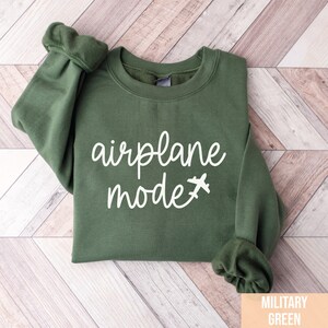 Pu&ograve; includere: Una felpa verde con la scritta "airplane mode" in lettere bianche e una piccola icona di aereo.
