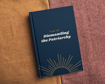 May include: A navy blue journal with the text "PLANS FOR Dismantling the Patriarchy" in white. A gold sunburst design is at the bottom. The journal is on a textured surface.