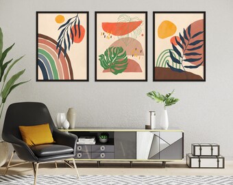 Op de afbeelding: Drie ingelijste abstracte kunstprints met een neutrale achtergrond en kleurrijke geometrische vormen en bladeren. De prints tonen een regenboog, een monstera-blad en een palmblad.