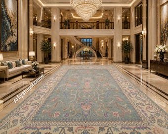 May include: A large, rectangular area rug with a light blue central field and intricate floral and geometric patterns in pink, beige, and blue. The rug is displayed in a grand, luxurious hall with marble flooring and a large chandelier.