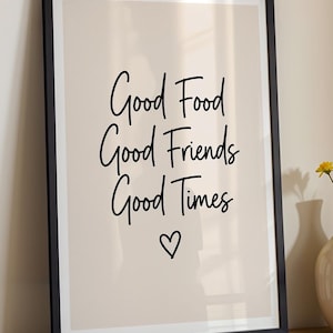 May include: A framed print with the words "Good Food Good Friends Good Times" in black script, with a heart symbol below. The background is a light beige color, and the frame is black.