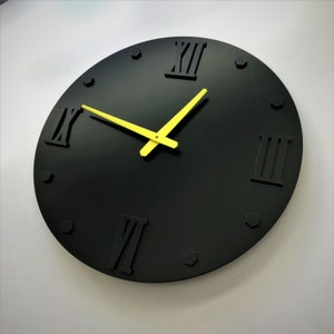 May include: A black clock with Roman numeral markings and yellow hands. The clock has a simple design and is perfect for a modern home.