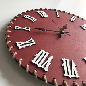 Peut inclure: Une horloge ronde rouge avec des chiffres romains et une bordure en corde noire. Les aiguilles de l'horloge sont noires.