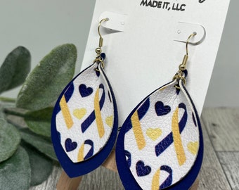 Puede incluir: Un par de pendientes colgantes con una base blanca y detalles azules y dorados. Los pendientes presentan un patrón de corazones y cintas. Los pendientes están en una tarjeta blanca con el texto "Molly Beth Made It, LLC".