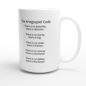 May include: A white ceramic mug with a curved handle. The mug features the text "The Kriegsspiel Code" and several lines of text below it. The text is in black and is centered on the mug. The mug is on a white background.