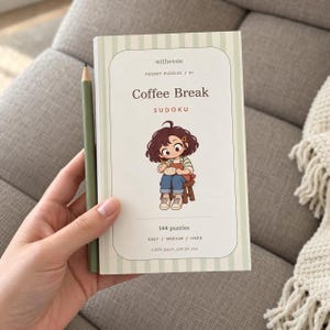 May include: A pocket-sized Coffee Break Sudoku puzzle book with a light green striped cover. The cover features the text withessie, POCKET PUZZLES / 01, Coffee Break, SUDOKU, 144 puzzles, EASY / MEDIUM / HARD, and a cartoon illustration.