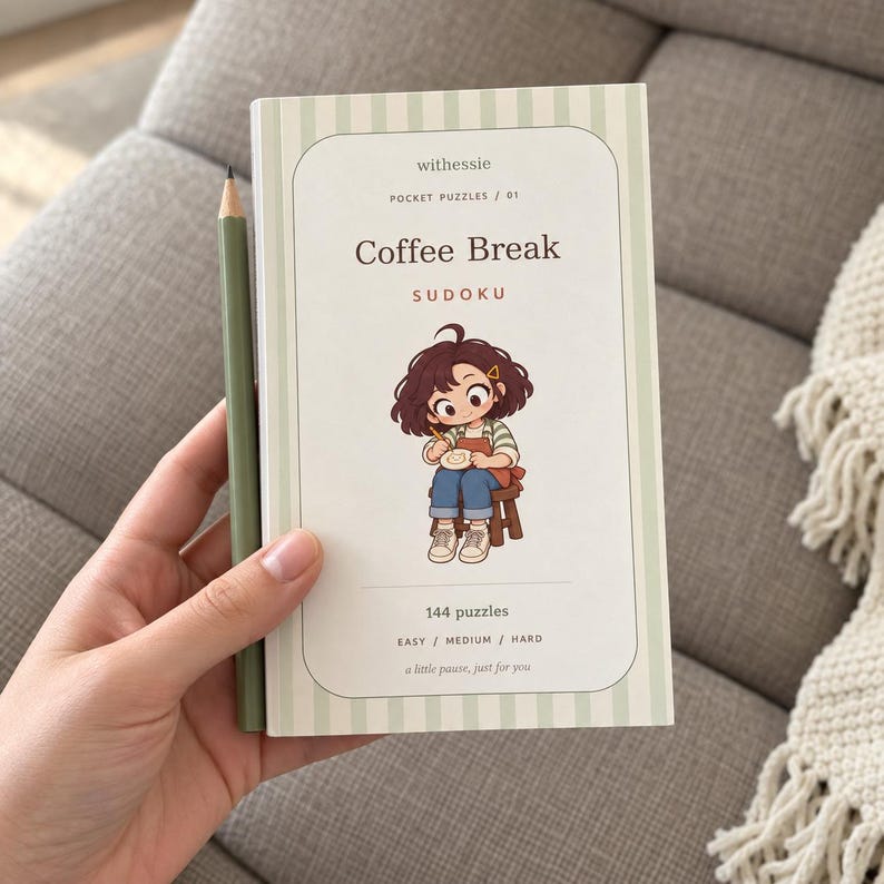 May include: A pocket-sized Coffee Break Sudoku puzzle book with a light green striped cover. The cover features the text withessie, POCKET PUZZLES / 01, Coffee Break, SUDOKU, 144 puzzles, EASY / MEDIUM / HARD, and a cartoon illustration.