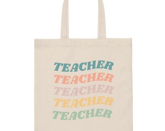 Può includere: Una borsa tote in tela naturale con la parola "TEACHER" ripetuta cinque volte in un arcobaleno di colori. Il testo è in uno stile di font retrò.