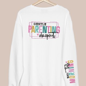 May include: White sweatshirt with the text "GENTLE PARENTING dropout" in colorful letters on the back and "EST. THIS MORNING" on the sleeve.