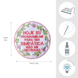 以下が含まれることがあります： 「HOJE EU PROGRAMEI-ME PARA SER SIMP&Aacute;TICA N&Atilde;O ME DISTRAIAS」の赤い文字が刺繍された、直径10cmの丸い白いパッチ。緑の葉と紫の花のフローラルボーダーが特徴です。