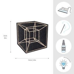 May include: Black embroidered patch featuring a geometric cube design with a gold outline. The patch measures 2 inches by 2 inches and is an exclusive design. Includes icons for ironing, sewing, and glue.