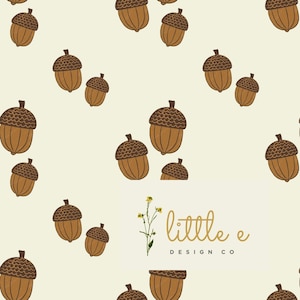 Pode incluir: Um padrão sem costura com bolotas marrons sobre um fundo amarelo claro. O padrão é repetido em toda a imagem. O texto "little e DESIGN CO" está no centro inferior da imagem.