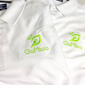 May include: Two white polo shirts with a green embroidered logo that says "GoMicro" on the left chest. The logo features a stylized leaf with a fork inside.