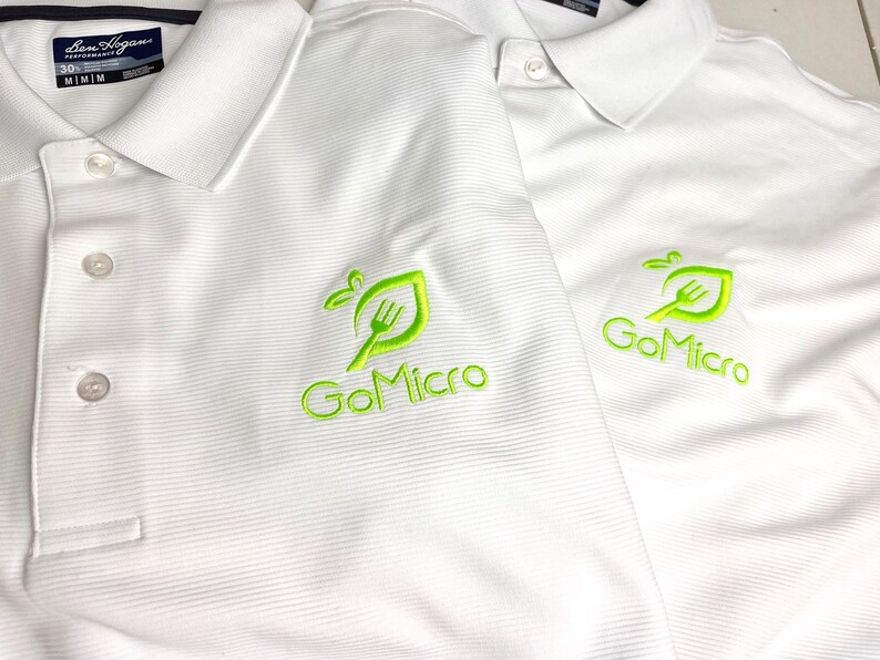 May include: Two white polo shirts with a green embroidered logo that says "GoMicro" on the left chest. The logo features a stylized leaf with a fork inside.