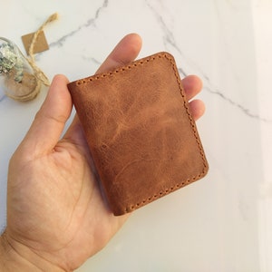 May include: A brown leather wallet with a stitched edge.