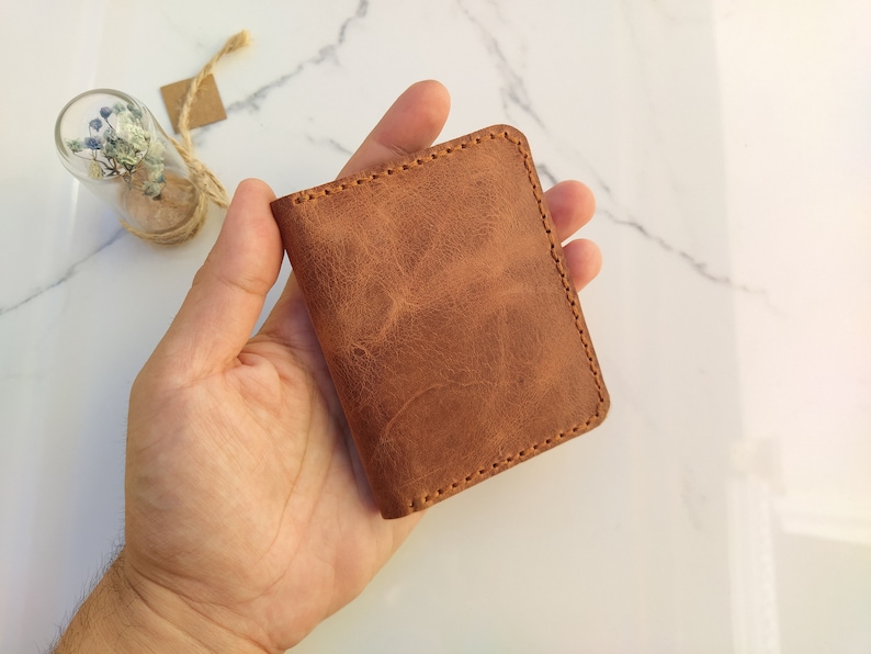 May include: A brown leather wallet with a stitched edge.