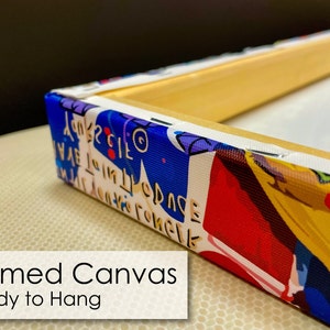 May include: Close-up of a framed canvas print with a colorful abstract design. The canvas is wrapped around the wooden frame and the edges are visible. The text "Framed Canvas Ready to Hang" is visible at the bottom of the image.