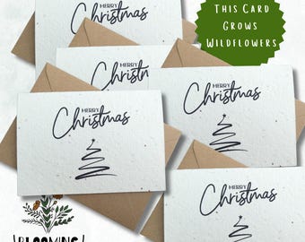 May include: A set of five white seed paper Christmas cards with brown envelopes. The cards feature a stylized Christmas tree and the text "Merry Christmas". The envelopes have the text "This Card Grows Wildflowers" on a green circle.