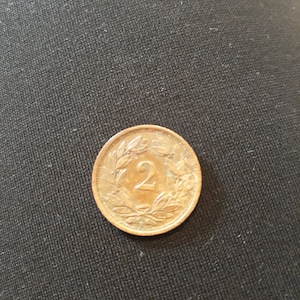 May include: A copper-colored coin with the number "2" in the center surrounded by a wreath of leaves.