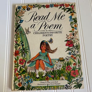 May include: Vintage children's book titled "Read Me a Poem" with a colorful floral border. The cover features an illustration of a girl in a blue dress, surrounded by flowers and butterflies. The book is a collection of children's favorite poetry.