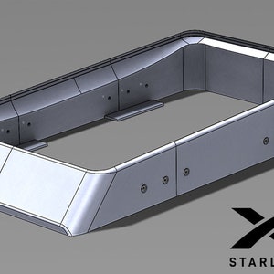 May include: A grey, rectangular, metal frame with rounded edges and a Starlink logo. The frame is designed to hold a device, possibly a satellite dish.