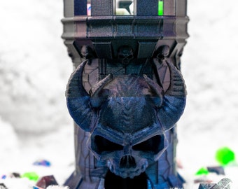 May include: A black and blue 3D printed dice tower with a skull and horns design. The tower is made to hold dice for tabletop games.