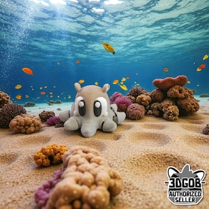 May include: A gray and white octopus-like figurine with large eyes sits on a sandy seabed, surrounded by colorful coral and small fish. The background shows clear blue water. The figurine has a cartoonish design.