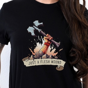 May include: Black t-shirt with a graphic of a hand holding an axe with the text "Just a flesh wound".
