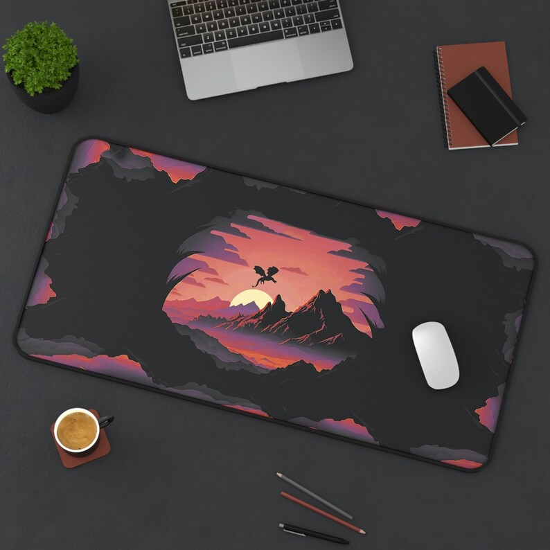 May include: A black and purple gaming mouse pad with a fantasy landscape design featuring a silhouette of a dragon flying over a mountain range. The design is set against a sunset sky with a dark cave in the foreground.