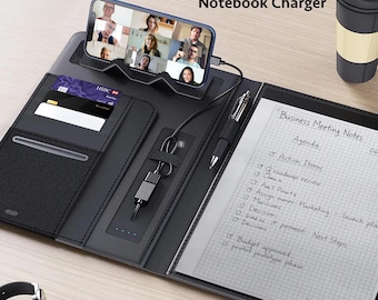 May include: A black notebook charger folio featuring a built-in phone stand, a charging cable, card slots, a pen holder, and a notepad with Business Meeting Notes text. The folio includes a smartphone displaying a video call and a black travel mug.