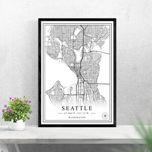 May include: Black and white map print of Seattle, Washington with the city's name and coordinates, "47.606°N / 122.33°W", printed below the map.