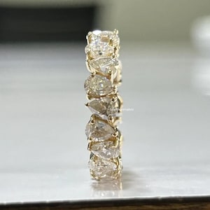Pode incluir: Um anel de banda de ouro com um design incrustado de diamantes em forma de pêra. O anel é engastado com múltiplos diamantes em forma de pêra.