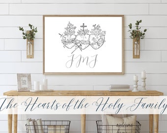 Pode incluir: Uma ilustração em preto e branco dos Sagrados Corações de Jesus, Maria e José. A imagem está emoldurada e pendurada em uma parede branca acima de uma mesa de consola de madeira. O texto "The Hearts of the Holy Family" está escrito em itálico abaixo da imagem.