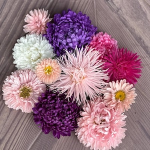 May include: A bouquet of pink, white, and purple flowers. The flowers are arranged in a circle on a wooden surface.