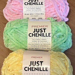 May include: Four skeins of Premier Just Chenille yarn in pastel colors: peach, pink, green, and yellow. Each skein is labeled with the text "For Crafters, Makers, Knitters, & Crocheters". The yarn is 65 yards / 60 meters and 1.76 oz / 50 g.