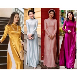 May include: Four women wearing long, traditional Vietnamese dresses called Áo dài. The dresses are in different colors: gold, light blue, pink, and magenta. Each dress has a side slit and pearl embellishments.