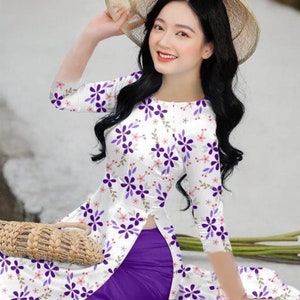 以下が含まれることがあります： 白い花柄の紫色のドレスと紫色のスカートを着た女性。彼女は麦わら帽子をかぶり、籐のバスケットを持っています。