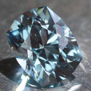 5.76 ct dark aqua colored lab sapphire. Precision cut elongated cushion design. Synthetic corundum, made by Czochralski method. 11 x 8.7 mm