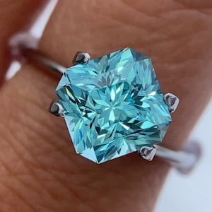 May include: A silver ring with a large, light blue, hexagonal-shaped gemstone. The gemstone has a starburst pattern.