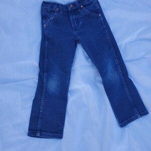 May include: A pair of dark blue denim jeans with a button fly and five pockets.