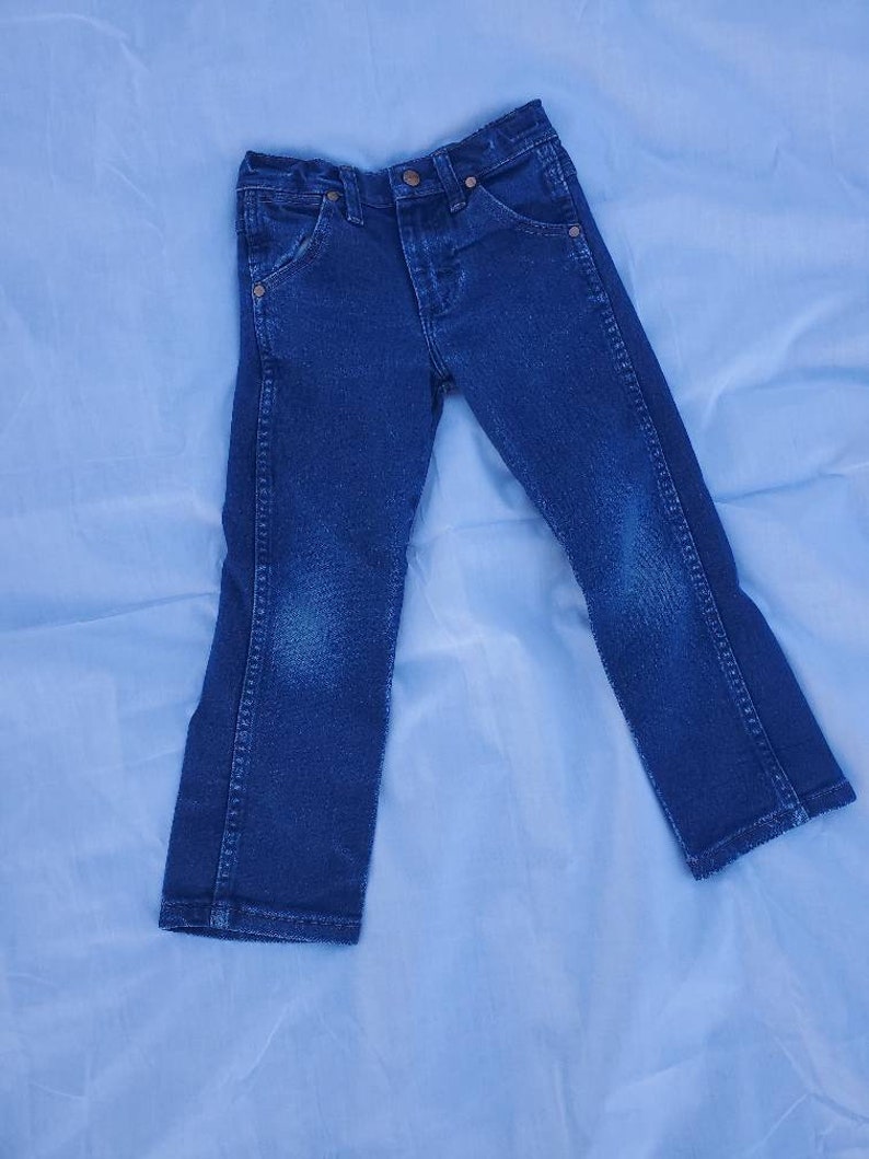 May include: A pair of dark blue denim jeans with a button fly and five pockets.