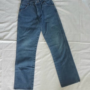 May include: A pair of blue denim jeans with a straight leg fit. The jeans have a classic five-pocket design and a button fly.