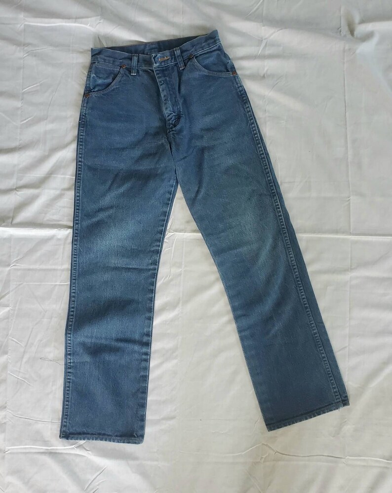 May include: A pair of blue denim jeans with a straight leg fit. The jeans have a classic five-pocket design and a button fly.